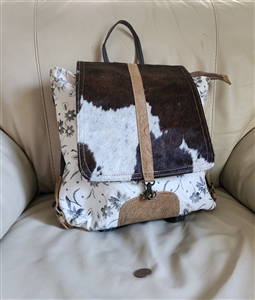 Myra Bag backpack with black and white cowhide hair on hide flap and upcycled floral canvas body with leather shoulder straps