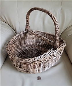 Large vintage handwoven willow wicker harvest basket showing thick bentwood overhead handle and dense weave structure