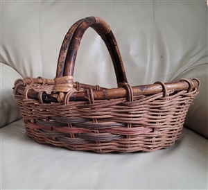 Handwoven willow wicker gathering harvest basket with arched handle showing low center walls and dyed side accent band