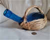 Vintage cobalt blue glass bottle nestled in a handwoven seagrass basket