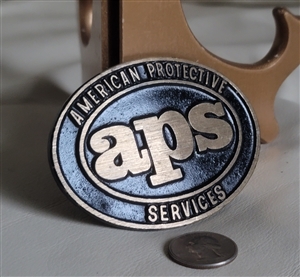 American Protective Services  APS belt buckle in black and gold colors with large emblem