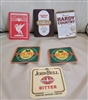 A diverse collection of vintage colorful beer mats in two different sizes featuring various brewery logos and branding
