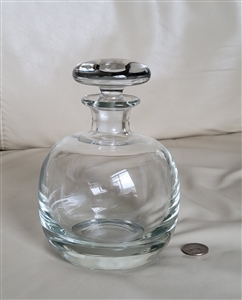Modern clear glass dome-shaped bottle decanter featuring a heavy flowing design and matching glass stopper for barware display