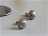Round sterling silver concho stud earrings with engraved feather nature design next to a coin for scale