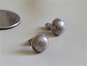 Round sterling silver concho stud earrings with engraved feather nature design next to a coin for scale