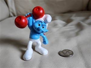 Front view of Blue Smurf Hefty 2011 McDonalds Happy Meal toy holding a red barbell weight overhead