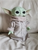 Front view of a Mattel Star Wars Grogu plush toy wearing robes next to a coin scale marker