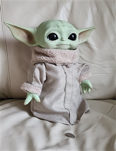 Front view of a Mattel Star Wars Grogu plush toy wearing robes next to a coin scale marker