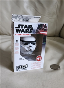 New old stock box displaying a white Star Wars Stormtrooper helmet mini bluetooth speaker next to a coin for size reference 2021