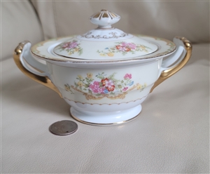 Noritake Muriel pattern porcelain lidded sugar bowl featuring pastel pink and yellow florals green leaves and ornate gold double handles from the 1930s