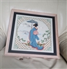Framed vintage Japanese cross stitch art featuring a Geisha with a blue kimono and umbrella in a mountain landscape