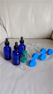 Vintage craft storage assortment with jumbo tubes, small glass bottles, and cobalt blue dauber bottles