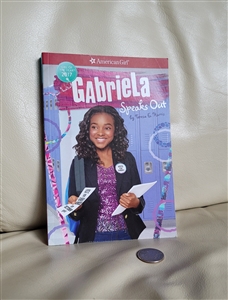 Front cover of American Girl book Gabriela Speaks Out showing a girl holding papers in front of school lockers