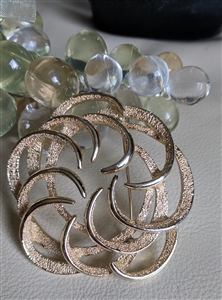 Authentic Sarah Coventry signed gold tone pin brooch with a shimmering textured geometric swirl design