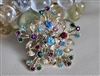 Vintage 1960s starburst pin for women with multicolor glass jewels and gold tone metal