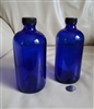 Pair of 1961 Swindell cobalt blue glass Boston Round apothecary bottles with black caps and 16 oz capacity