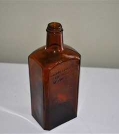Vintage Bodegas California amber glass paneled spirit bottle standing approximately 9 inches tall with embossed post-Prohibition warning and rectangular base