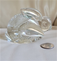 A clear vintage art glass bunny paperweight with internal controlled bubble inclusions shown next to a coin for scale comparison