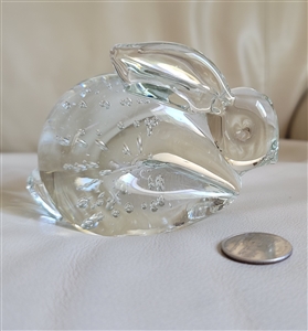 A clear vintage art glass bunny paperweight with internal controlled bubble inclusions shown next to a coin for scale comparison