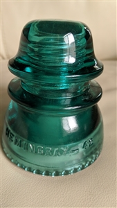 This preowned vintage green glass Hemingray 42 utility insulator features a classic bell shape and industrial design