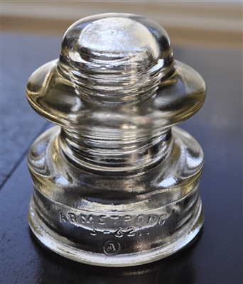 This preowned vintage Armstrong 51-C1 clear glass utility insulator features its classic industrial embossed design