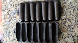 Top and back views of two vintage Wagner Ware cast iron corn shaped baking pans showing aged iron finish and manufacturer marks