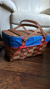Vintage woven picnic basket featuring a solid wooden lid drop handles and blue cloth liner