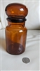 1970 Belgian amber glass apothecary storage bottle showing bobble lid and swirled base