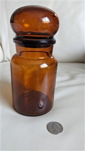 1970 Belgian amber glass apothecary storage bottle showing bobble lid and swirled base