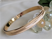 Vintage Monet gold tone bangle bracelet with etched diamond cut satin finish and polished edges