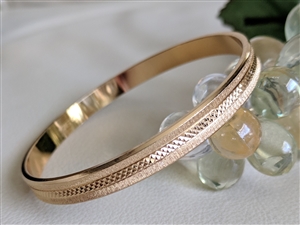 Vintage Monet gold tone bangle bracelet with etched diamond cut satin finish and polished edges