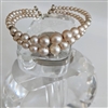 Vintage peach faux pearl double strand bypass cuff bracelet showing wire patina and graduated beads