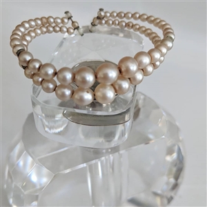 Vintage peach faux pearl double strand bypass cuff bracelet showing wire patina and graduated beads