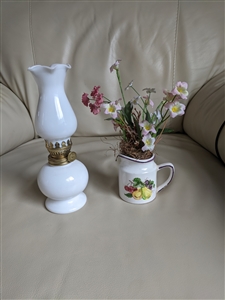 Preowned vintage small white milk glass oil lamp next to a ceramic fruit measuring cup pitcher with artificial flowers