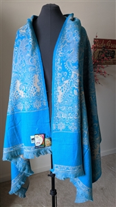 Handmade turquoise and beige wool shawl from India draped on a mannequin with reverse design and fringes.