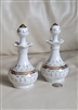 Detailed close-up shot of a matching vintage white porcelain vanity perfume bottle featuring an ornate ribbon-scalloped neck, bulbous body adorned with intricate hand-painted gold-tone scrollwork and raised enamel dots, and a matching pointed finial stopp