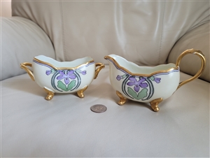 Art Nouveau hand painted porcelain creamer pitcher and open sugar bowl set with purple iris medallions and four gold feet