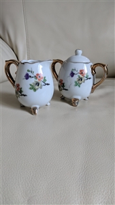 Enesco Japan miniature white porcelain creamer and lidded sugar bowl set with hand painted florals and gold tripod feet from the 1960s