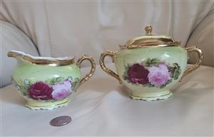 O and EG Royal Austria antique porcelain lidded sugar bowl and creamer set in green with hand-painted roses and gold trim from the 1900s