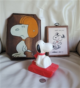 Three piece vintage Peanuts set with a plastic Snoopy bottle a hand painted wood plaque and a Corton Sproke decoupage plaque