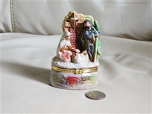 Colorful porcelain nativity scene trinket box showing Mary Joseph and baby Jesus with gold tone metal accents