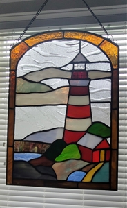 Vintage handcrafted stained glass window panel featuring a nautical lighthouse and seaside design, Close up of 13.5 inch lighthouse suncatcher showing a visible crack in the top glass panel, View of sunlight shining through coastal lighthouse stained glas