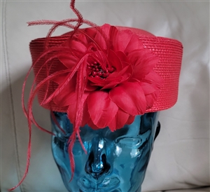 Vintage red pillbox hat with woven design and floral accent decor
